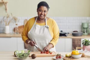 waist-up-portrait-young-black-woman-cooking-healthy-salad-kitchen-cutting-vegetables-copy